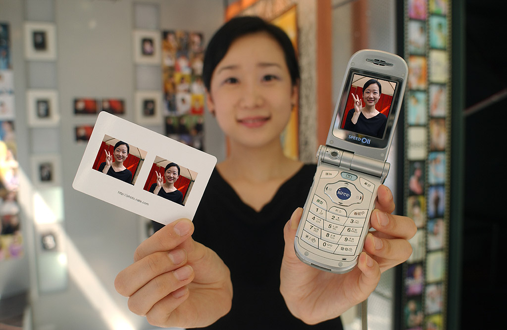 One of the customers is shown taking a look at printed photo taken by cellular phone through SK Telecom?s Mobile Printing Service